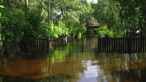 Flooded spring or summer landscape. Water covering all sidewalks and roads, private houses and green yards. 4k video of real flooded landscape. May, Ukraine