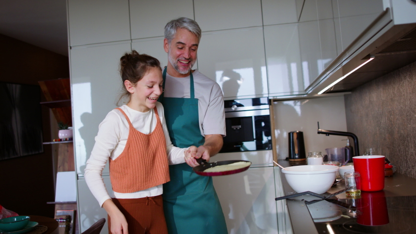 Teenage daughter with her father cooking in kitchen together. Royalty-Free Stock Footage #1090739873