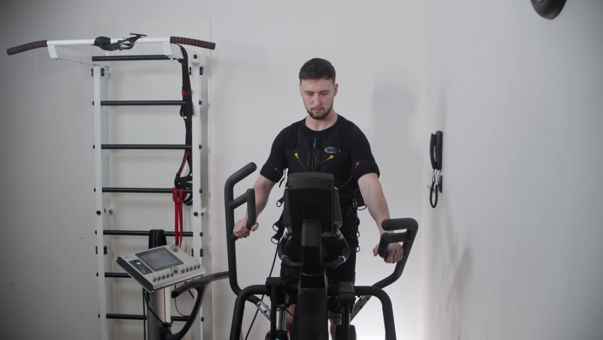 A man wearing electro-stimulation suit and training on exercise bike