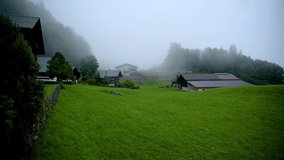 4k Timelapse video of moving clouds over the wooden chalet farm houses situated at the alpine village of Hasliberg ,Switzerland on a foggy evening. The transition from light to dark can be seen.