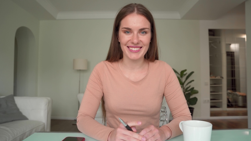 Web cam view on woman talking to camera gesturing sitting at home office table. Vlogger shooting vlog, mentor coach holding video call, job sicker making online interview self recording presentation