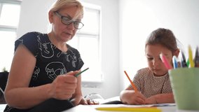 Mature woman granny with grandchild preschool girl drawing together at home. Lifestyle stable shot video 