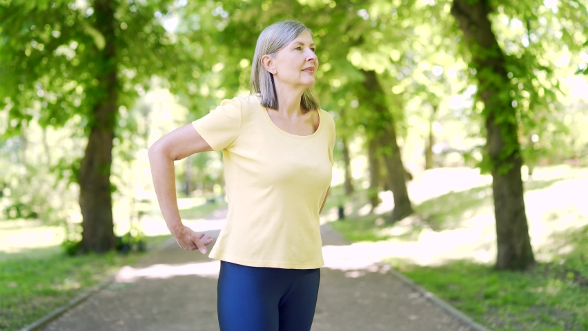 senior woman back pain in the park outdoors while jogging. Worried upset mature female feel hurt sudden ache. Upset eldery person suffering backache, unhappy lady lumbar hurt in the spine or lower Royalty-Free Stock Footage #1090749505