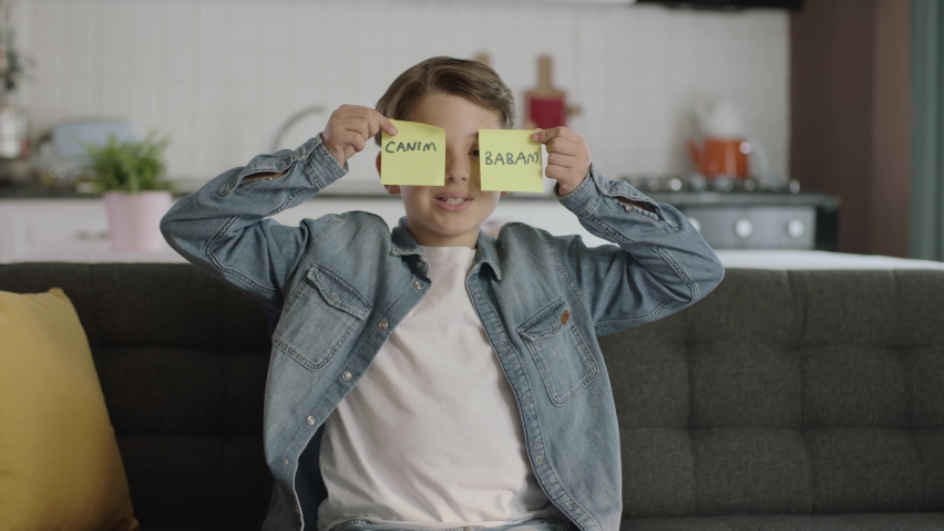 Mother's day, father's day, romantic concept.Message video of a happy kid holding paper notes with "dear dad" in Turkish over his eyes. | Shutterstock HD Video #1090749701