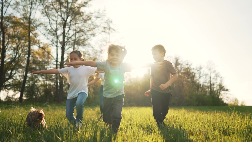 Children play in spring vacation park.Active happy group of kid run with a dog on grass in field in summer.Family in nature with pet.Child on play.Happy family concept.School in garden with dog Royalty-Free Stock Footage #1090750105