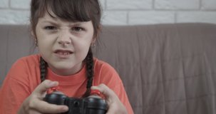 Play game using joystick. An upset little girl hold her joystick and play game online.