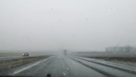 Belarus, 17 November 2021. Bad driving conditions on a highway in wet snow and rainy weather. Blurry car front view. Traffic. Slippery road. Difficult visibility. Windscreen wiper. Moving automobiles.