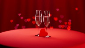 Two chilled champagne glasses are full of white sparkling wine. Cold droplets gathered on a surface. Red background with nice heart shape bokeh depth of field effect. Camera track in. - Powered by Shutterstock - Get 15% off with code: PIKWIZARD15