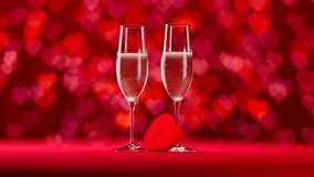 Two chilled champagne glasses are full of white sparkling wine. Cold droplets gathered on a surface. Red background with nice heart shape bokeh depth of field effect. Camera rotates - Powered by Shutterstock - Get 15% off with code: PIKWIZARD15