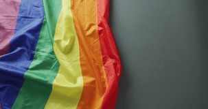 Video of creased rainbow flag lying on black background. gay pride, lgbt rights and supporting minority concept.