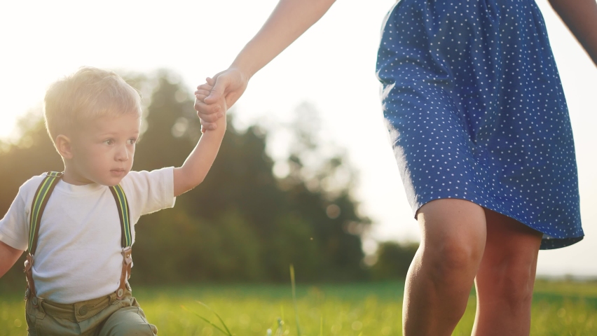 happy family mom and son a walk hold hands in the park. mother and boy kid together hands at sunset. parent and boy walk child fun in nature park. happy childhood. happy family mother day concept Royalty-Free Stock Footage #1090763975