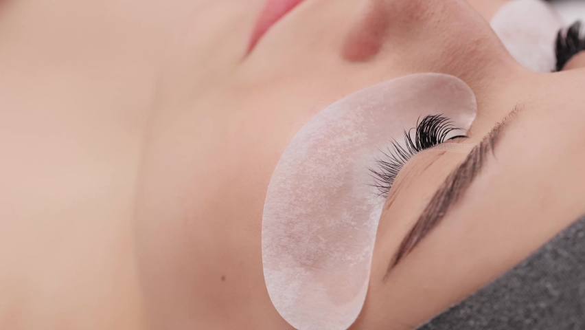 Eyelash extension procedure. The working process of professional beauty master lengthening female lashes. Fake eyelashes. Eyelashes extensions close up. Makeup artist and client in beauty salon. Royalty-Free Stock Footage #1090764701