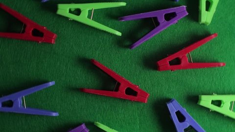 Colored clothespins on a green textured background, top view, close-up, bright backdrop.