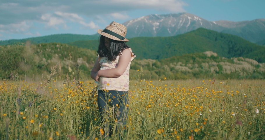 Little girl wearing hat in a sunny meadow.