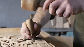 the male hands of a wood carving master holding a sharp awl with a wooden handle strikes with a wooden hammer and creates beautiful patterns on the board. Slow motion, close up. Hobby, craft - Powered by Shutterstock - Get 15% off with code: PIKWIZARD15