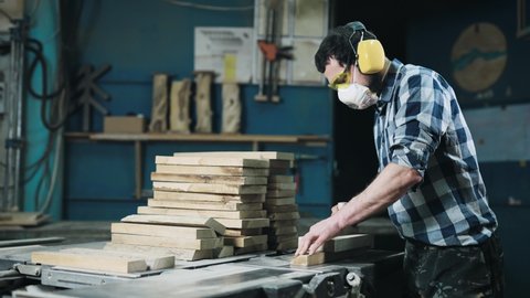 A man works with a planer. The carpenter uses personal protective . Craft