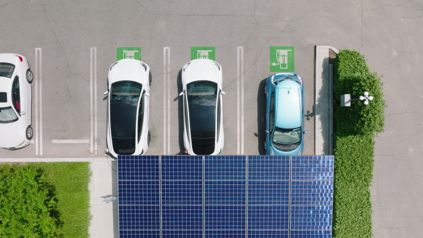 Modern electric car at renewable power solar batteries charging station. Aerial solar panels at urban parking landscape. Futuristic self driving, zero emission and pollution car at EV supercharger 4K Royalty-Free Stock Footage #1090776991