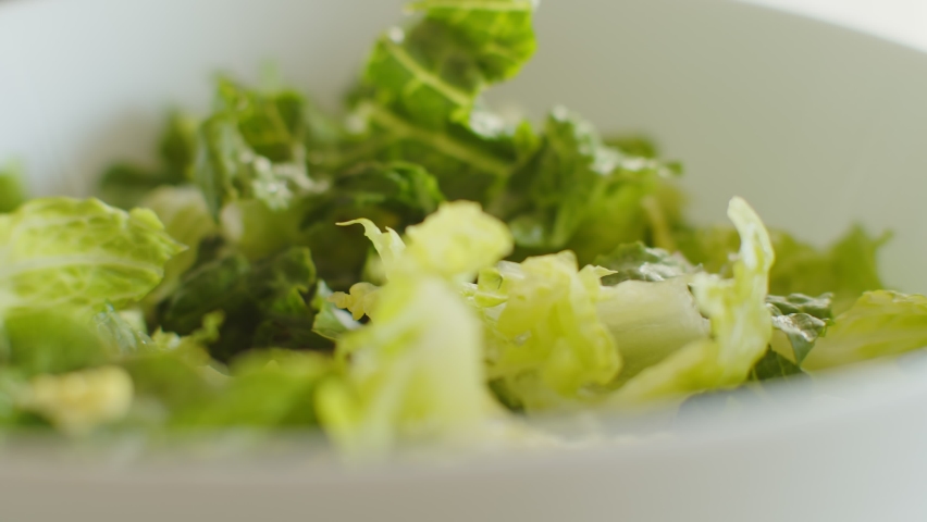 Pour dressing on a Caesar salad. Camera slider shot. 4K footage.