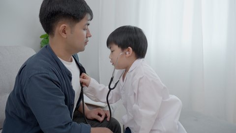 A boy plays the doctor recheck healthy for father on weekend. The boy has a dream in a doctor's career. The concept of family activities and the dream career.
