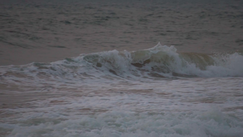 Slow motion of a huge sea wave forming and crashing at the Baga beach in Goa, India. Sea wave crashes on the beach. Powerful big sea wave crashes on the sea shore due to high winds in stormy weather.