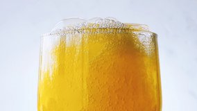 Orange soda is pouring into a glass with ice cube close-up on a white wall background. Overflowing wet glass with pop orange soda. 4k macro raw video 60 fps.	 - Powered by Shutterstock - Get 15% off with code: PIKWIZARD15