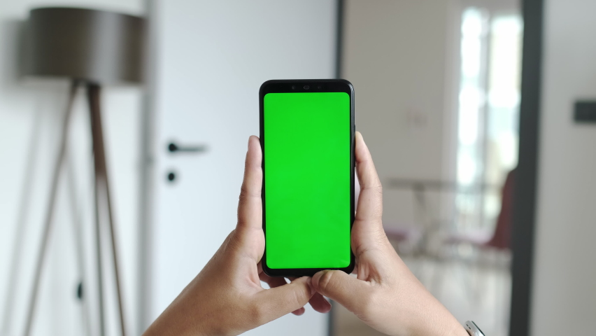 Handheld Camera: Point of View of Young Woman at Cozy Apartment Using Phone With Green Mock-up Screen Chroma Key Surfing Internet Watching Content Videos Blogs Tapping or Click on Bottom of the Screen Royalty-Free Stock Footage #1090792909