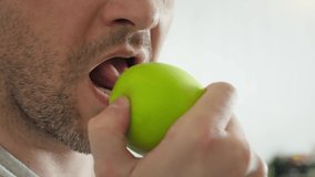 man eating green apple close up slow motion. unshaven guy eats apple, chews it slowly, whole face is not visible. young man mouth eating an apple. fruit light snack. mouth bite an apple. Be H3althy
