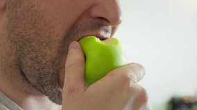 man eating green apple close up slow motion. unshaven guy eats apple, chews it slowly, whole face is not visible. young man mouth eating an apple. fruit light snack. mouth bite an apple. Be H3althy