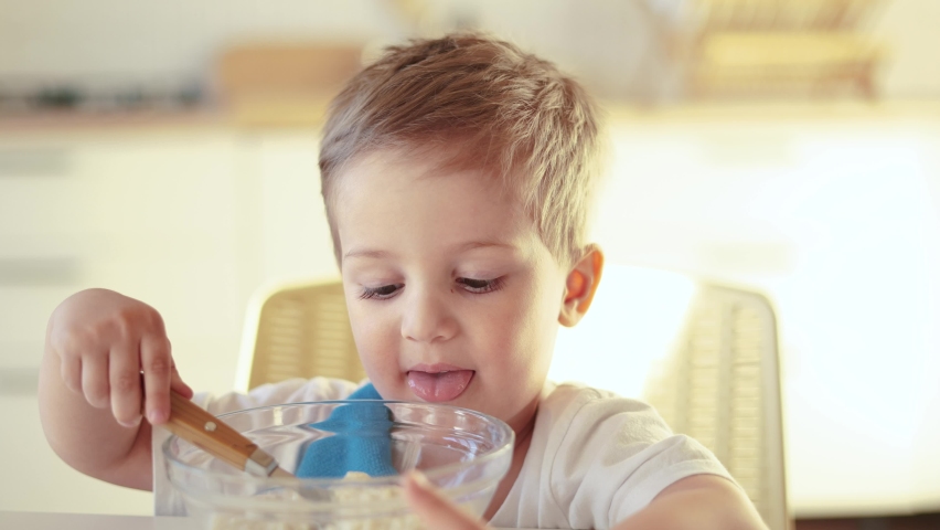 the child does not want to eat porridge. happy family healthy food concept. the boy little son eats porridge with a spoon soiled in his face. child dirty dirty eating porridge lifestyle funny video
