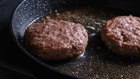 Chef hand puts rosemary into the frying pan with beef burgers patty. Cooking food concept. 4k video