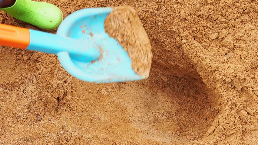 blond kid digs a hole in the sandbox with a plastic shovel Royalty-Free Stock Footage #1090801591
