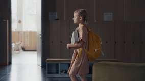Dejected schoolgirl walking holding books in empty hallway after classes alone. Thoughtful elementary age pupil passing lightened modern classrooms. Focused blonde girl worrying about school study.  - Powered by Shutterstock - Get 15% off with code: PIKWIZARD15