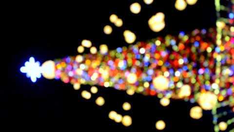 New Year's Christmas tree decorated with luminous multi-colored garlands and illumination at night. Christmas tree with flashing lights. Blurred background. New Year Christmas holidays. Vertical video