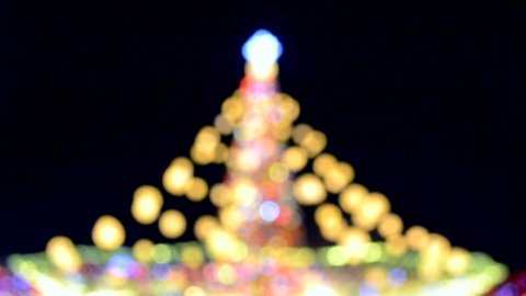 Large New Year's Christmas tree decorated with luminous multi-colored garlands and illumination at night. Christmas tree with flashing lights. Blurred background. New Year and Christmas holidays