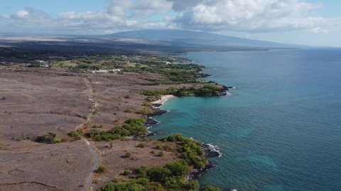 4K cinematic drone shot of the desert and volcano in the background on the coast near Kona on the Big Island of Hawaii. This vibrant scene was filmed using a DJI Mini 2 drone.