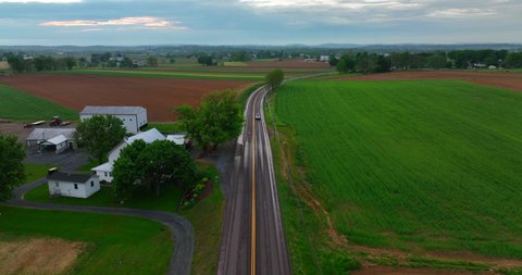 Aerial tracking shot of car on wet roads. Rural countryside after rain storm. Drone shot in American agriculture area.