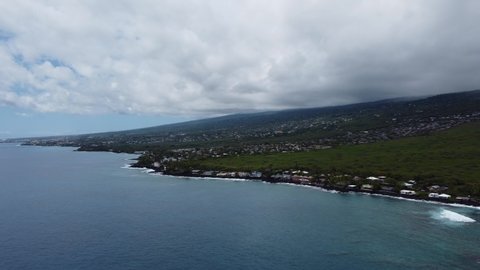 4K cinematic pan drone shot of the tropical lava rock coastline in Kona on the Big Island of Hawaii on a cloudy day. This relaxing shot of waves headed towards shore was filmed using a DJI Mini 2.
