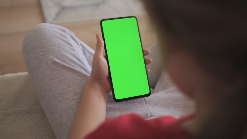 Phone With Green Mock-up Screen Chroma Key Surfing Internet Watching Content Videos Blogs Learning. Girl Playing Video Games. Point of View of Child at Living Room Using Phone With Green Mock-up.  Royalty-Free Stock Footage #1090808441