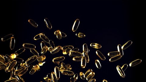 Omega 3 vitamin capsules soar up and fall down. On a black background. Filmed on a high-speed camera at 1000 fps.