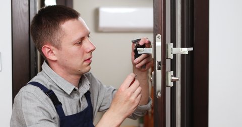 a man repairing a door knob. locksmith fixing a wooden door. High quality 4k footage