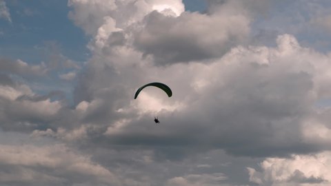 paragliding in tandem over flat fields in cloudy weather