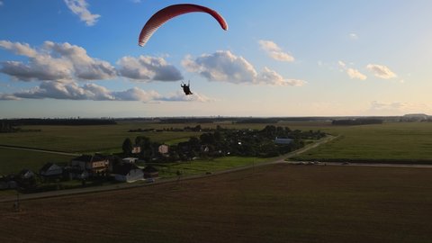 paragliding in tandem over flat fields in sunny weather