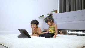 Slow motion shot, Two Asian Lovely girls enjoy and laugh during watching movie on Tablet in living room