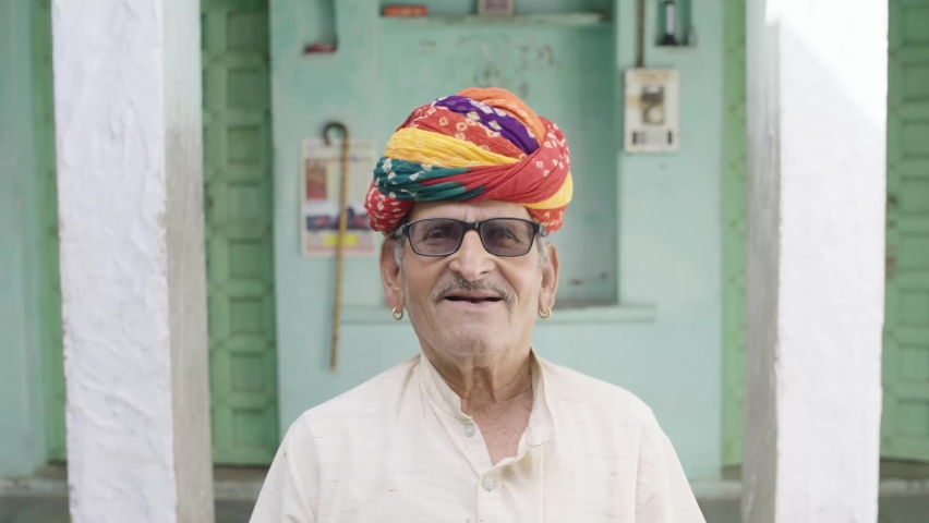 An old happy Indian village man in a colorful turban looking at the camera.