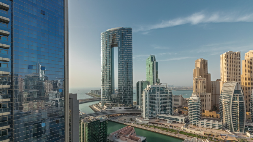 Panorama showing Dubai Marina skyscrapers and JBR district with luxury buildings and resorts aerial timelapse. Waterfront with palms and boats floating in canal Royalty-Free Stock Footage #1090818517