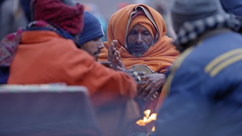 Kedarnath , India - 11 12 2021: Close up of pilgrims sitting by campfire in cold day. Gimbal, shallow focus.