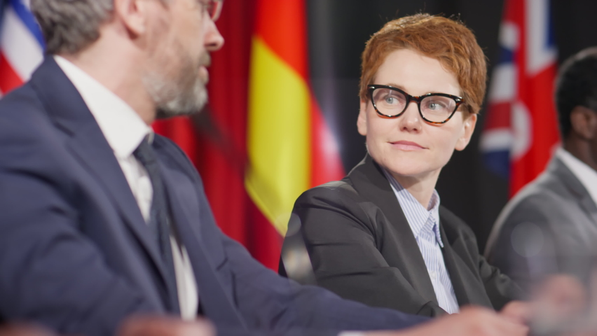 Selective focus shot of young female politician speaking with middle aged colleague during international press conference | Shutterstock HD Video #1090822939