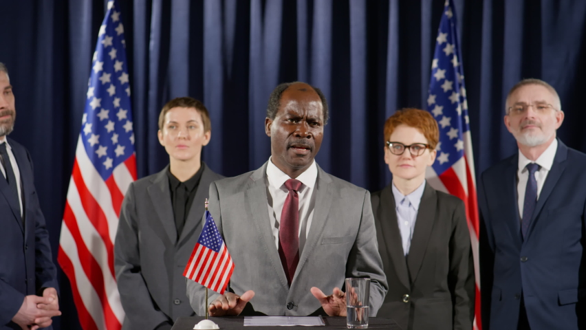 African American president standing at rostrum with US flag on it and speaking in mic while making public announcement during press conference