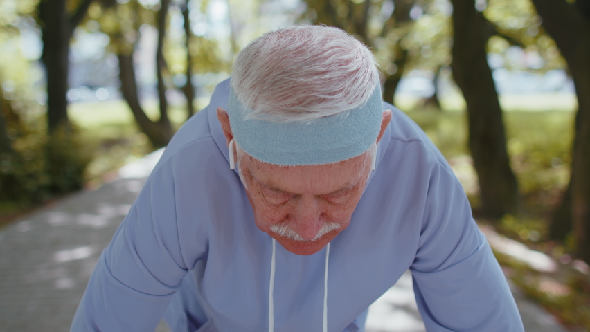 Athletic fitness senior man starting running race in sunny park. Active elderly grandfather jogging in summer forest during morning workout outdoors. Active retirement, sport healthy lifestyle concept Royalty-Free Stock Footage #1090824953