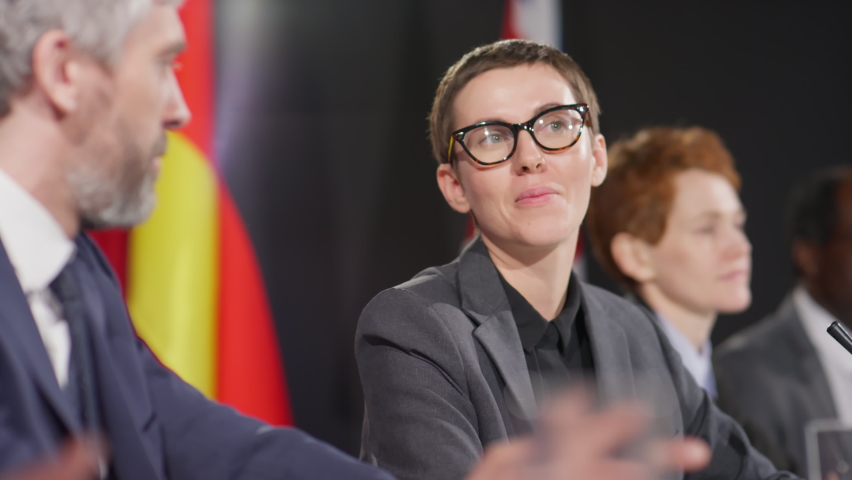 Selective focus shot of young female politician speaking with male colleague during international press conference | Shutterstock HD Video #1090826623